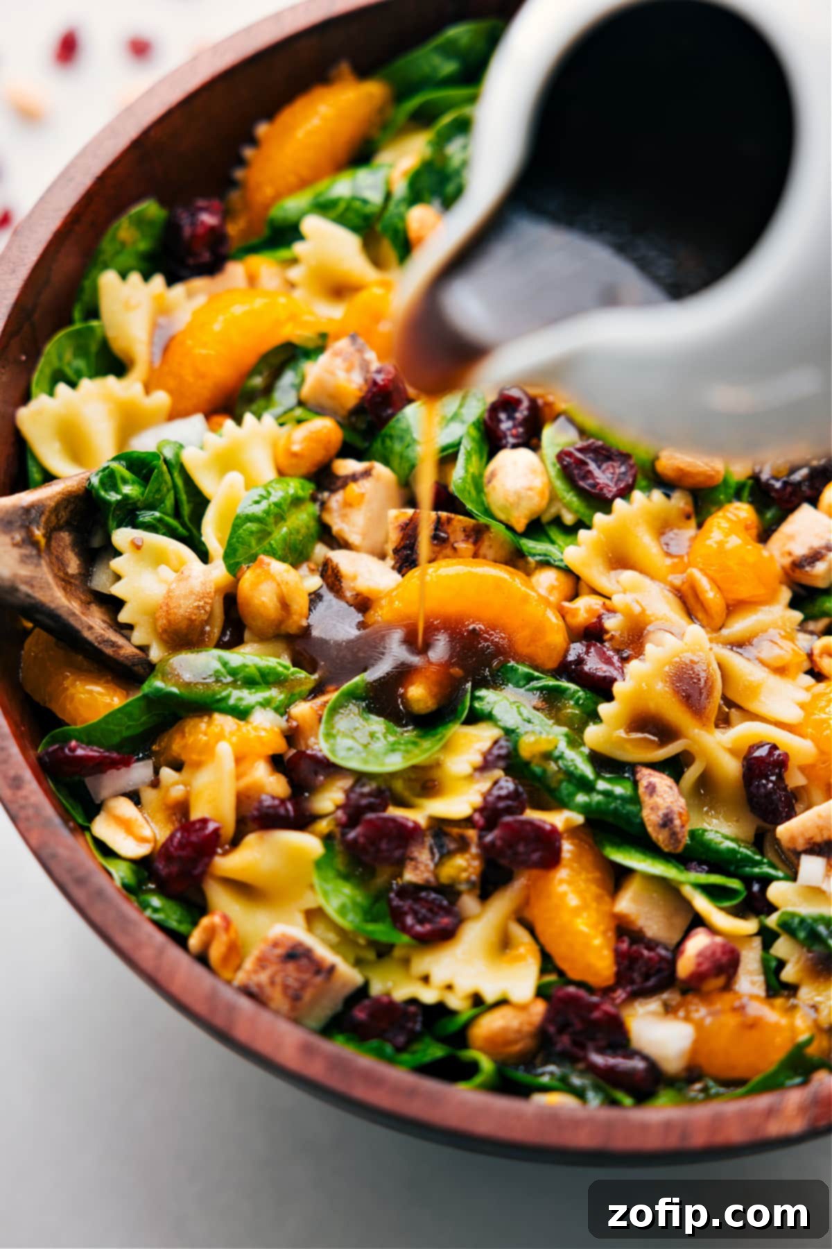 Teriyaki Chicken Salad dressing being poured over the dish, ready to be tossed together and served, highlighting the rich texture.