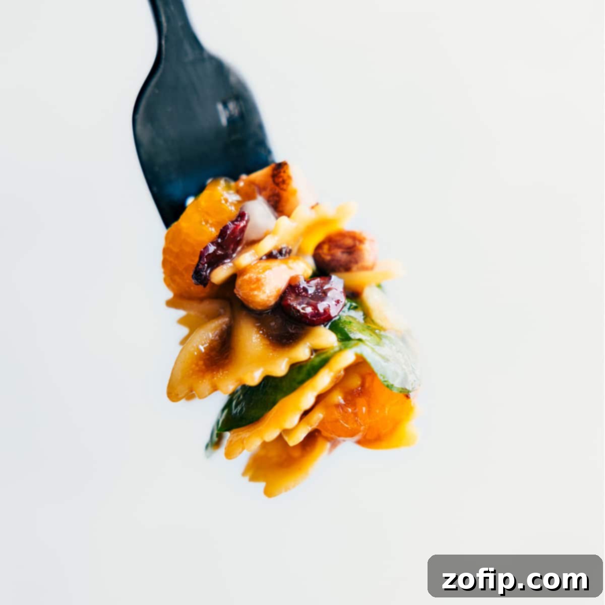 A forkful of the Teriyaki Chicken Salad showing all the different parts of this delicious recipe, including pasta, chicken, oranges, and spinach.
