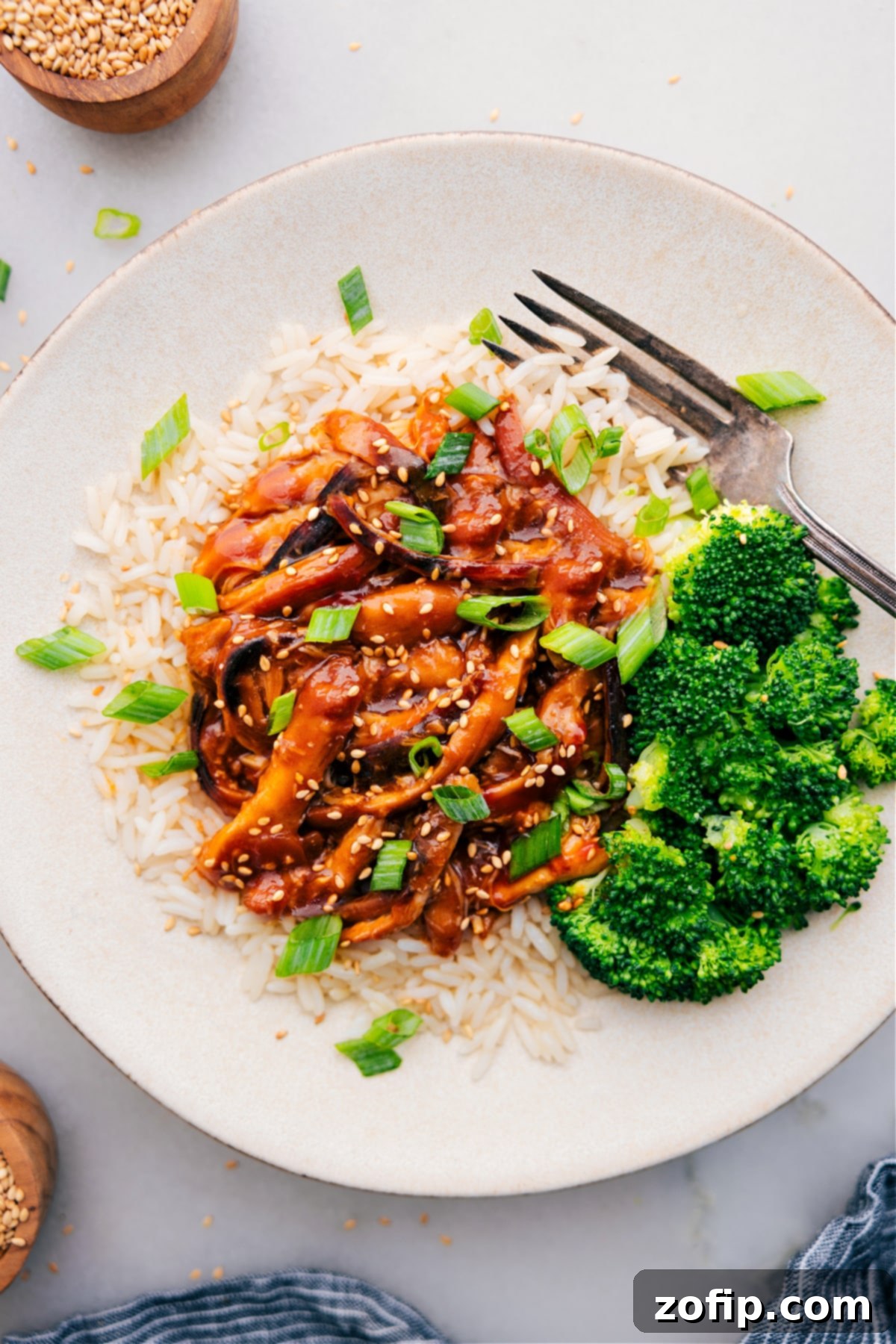 Honey Garlic Chicken Thighs served on a bed of rice, accompanied by roasted broccoli on the side and topped with fresh green onions for a vibrant garnish.