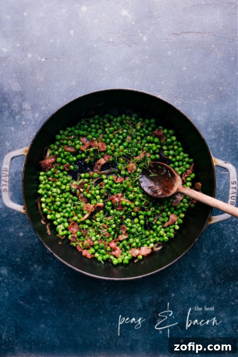 This Frozen Peas recipe is a total show-stopper! With crisp bacon, caramelized shallots, and a touch of garlic--you'll never want frozen peas any other way! Recipe via chelseasmessyapron #sidedish #best #quick #easy #simple #bacon #frozenpeas #recipe Overhead image of a vibrant dish of Frozen Peas with bacon and shallots, ready to be served.