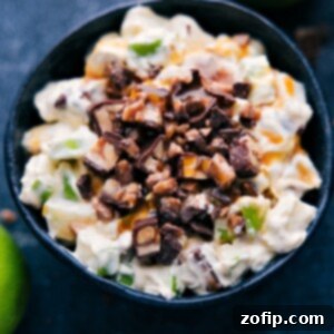A bowl of creamy Snickers Salad garnished with extra Snickers pieces, a perfect easy dessert.