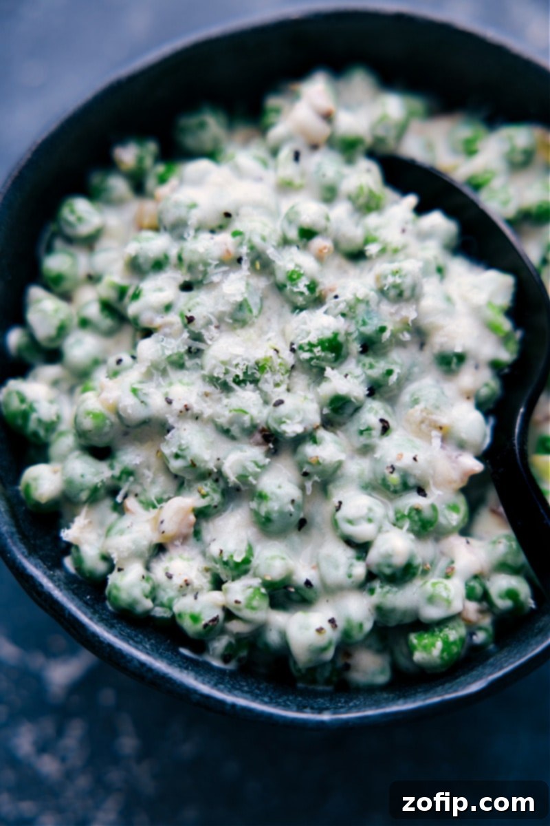 A delectable serving of Creamed Peas, perfectly garnished and ready to be savored. Up-close overhead image of a single serving of Creamed Peas in a small white bowl, garnished with a sprig of fresh parsley, steam rising slightly.