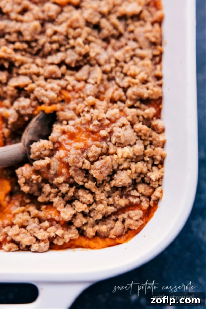 Delicious Sweet Potato Casserole with Streusel Topping Overhead view of a golden-brown Sweet Potato Casserole with a crispy streusel topping, ready to be served from a white baking dish.