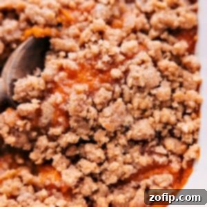 Ultimate Sweet Potato Casserole 2 Close-up shot of the finished Sweet Potato Casserole with a glistening streusel topping, served in a white baking dish.