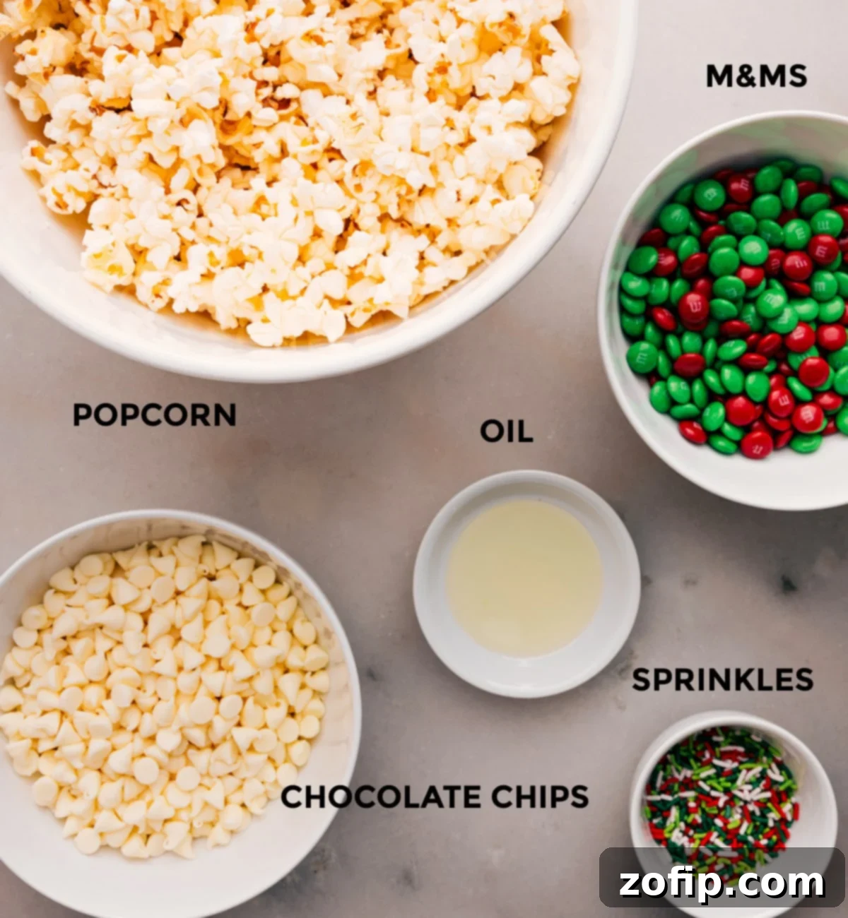 Ingredients In Christmas Popcorn Recipe Prep all the ingredients for easy assembly: M&Ms, oil, sprinkles, popcorn, and white chocolate.