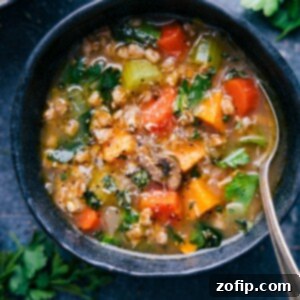 A close-up of a steaming bowl of hearty Farro Soup, garnished with fresh herbs, showcasing the rich texture of the farro and vegetables.