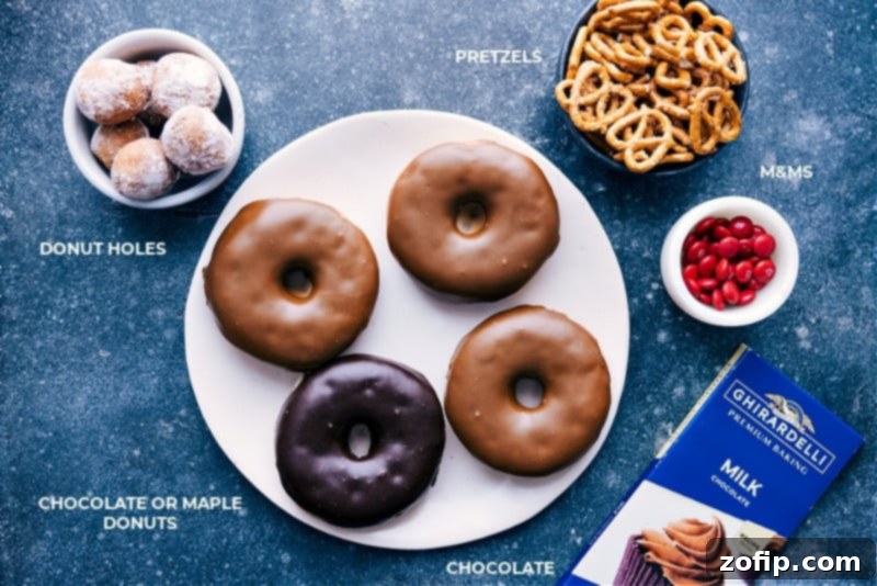 All the simple ingredients you need to create your own festive Christmas Reindeer Donuts at home. Ingredient shot for Christmas Donuts, showing chocolate melting wafers, pretzels, M&Ms, and donut holes.