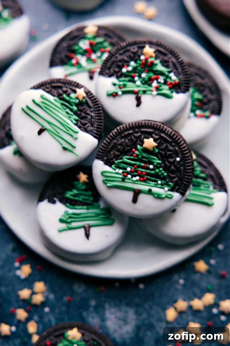 Overhead image of a platter featuring four different Christmas Oreo designs: Christmas trees, melted snowmen, Rudolph reindeer, and festive ornaments.