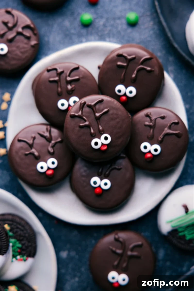 Overhead image of adorable Rudolph the Red-Nosed Reindeer Christmas Oreos, featuring edible eyes, a red M&M nose, and chocolate antlers.