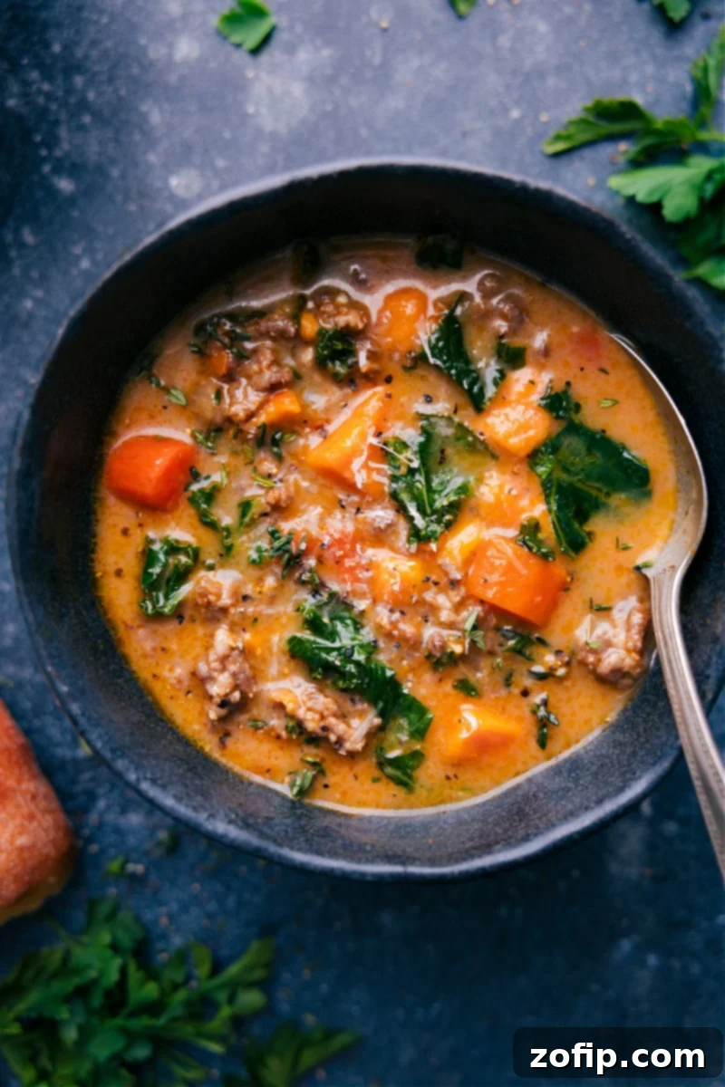 Overhead image of a steaming bowl of Healthy Zuppa Toscana Soup, garnished with fresh herbs.