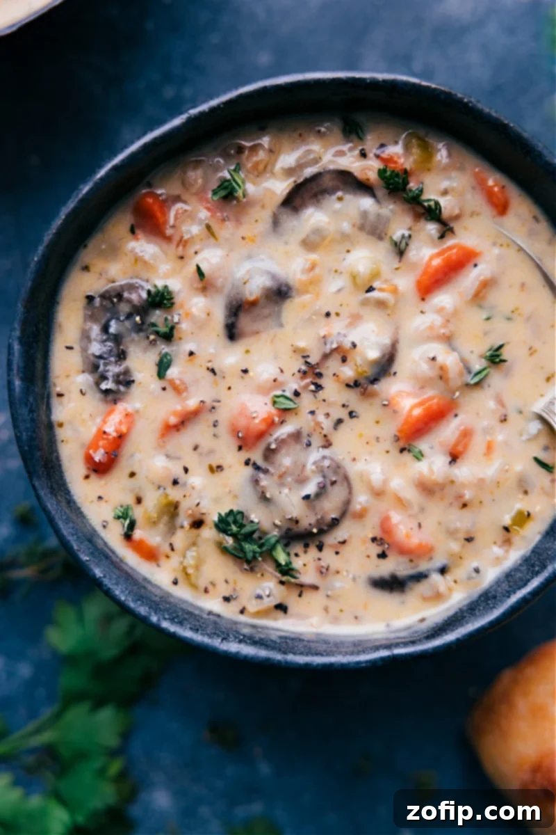 Creamy Mushroom Carrot Farro Soup: A hearty, savory, and wholesome comfort meal for winter. Overhead image of a bowl of creamy mushroom soup with fresh herbs and crusty bread