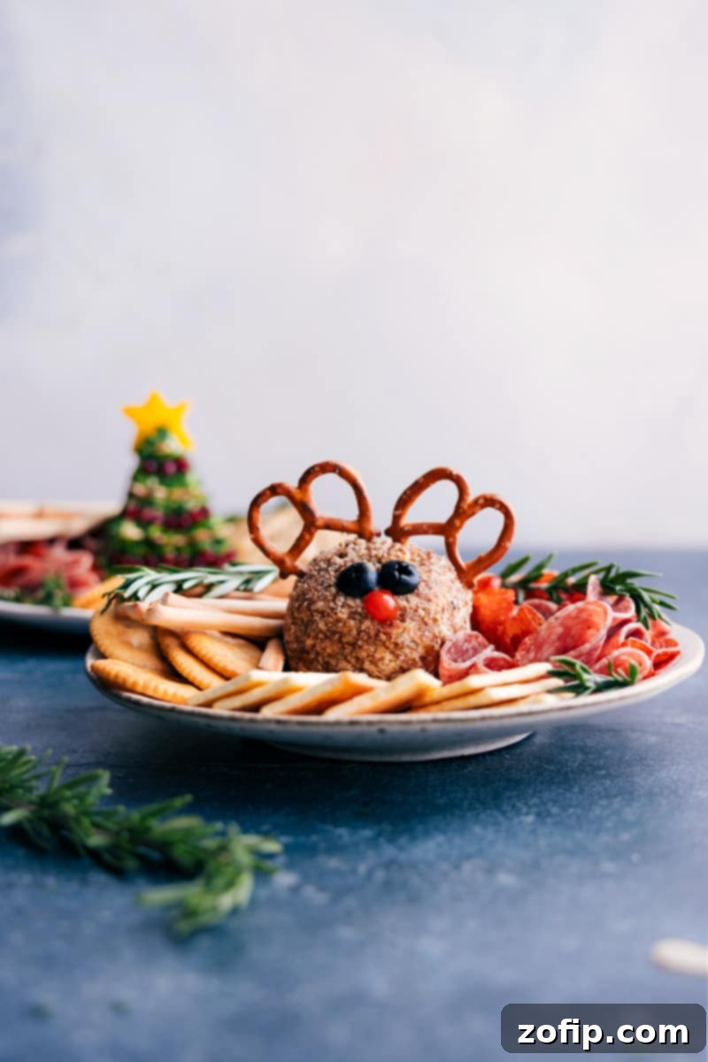 Rudolph the Reindeer cheeseball presented beautifully on a festive Christmas platter with an assortment of crackers, fresh vegetables, and cured meats.