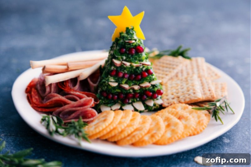 The festive Christmas Tree cheeseball on a serving platter surrounded by an array of dippers, ready to be enjoyed at a holiday party.