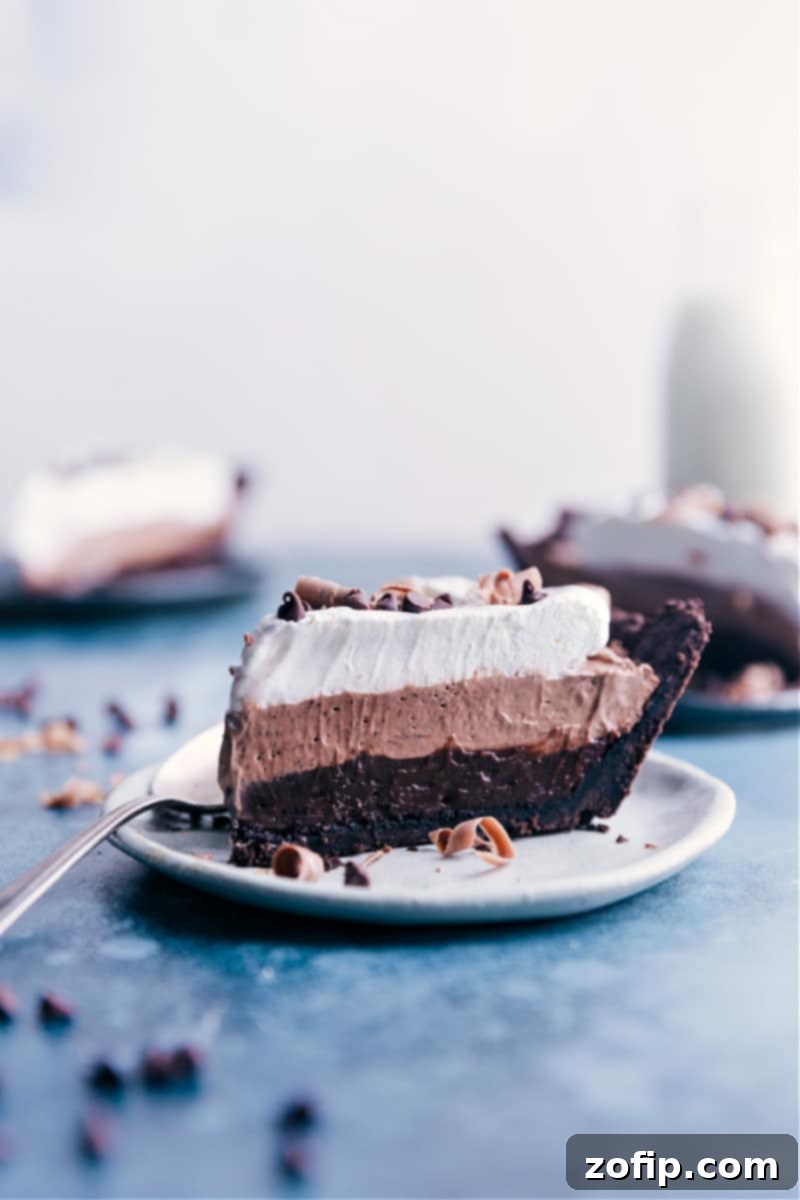 Velvety Chocolate Cloud Pie 9 A beautiful slice of No-Bake Chocolate Pudding Pie, showcasing its three distinct, creamy layers and crunchy Oreo crust, ready for serving.