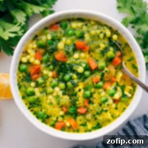 Couscous Soup Cold Buster 2 A close-up of a bowl of homemade Chicken Pearl Couscous Soup, garnished with fresh parsley and a slice of lemon, ready to be enjoyed.