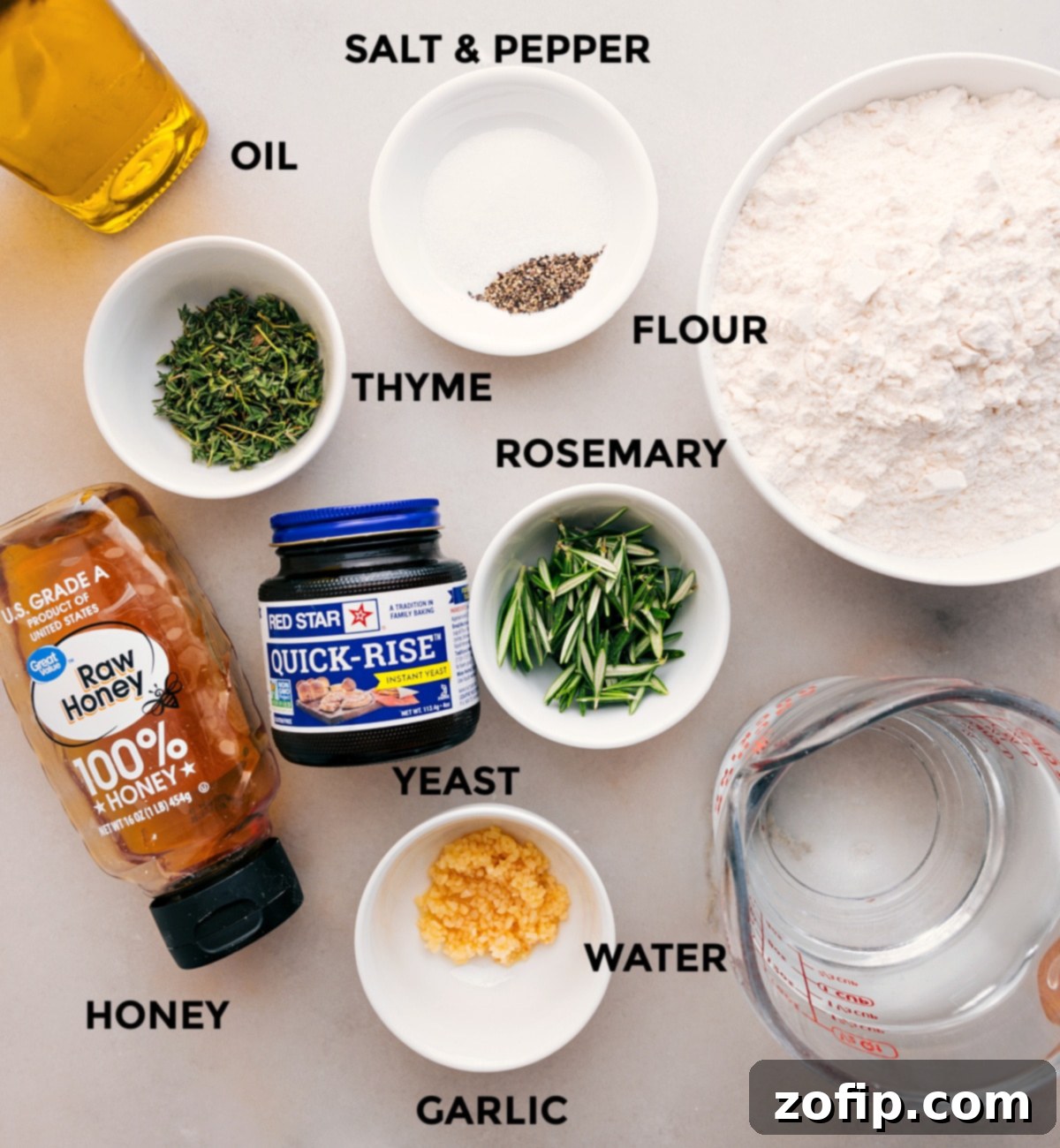 All the fresh ingredients for No-Knead Herb Bread laid out: flour, olive oil, fresh thyme, fresh rosemary, yeast, warm water, and honey.