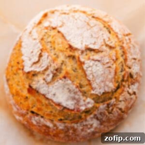A freshly baked loaf of No-Knead Herb Bread, golden and rustic, ready for serving.