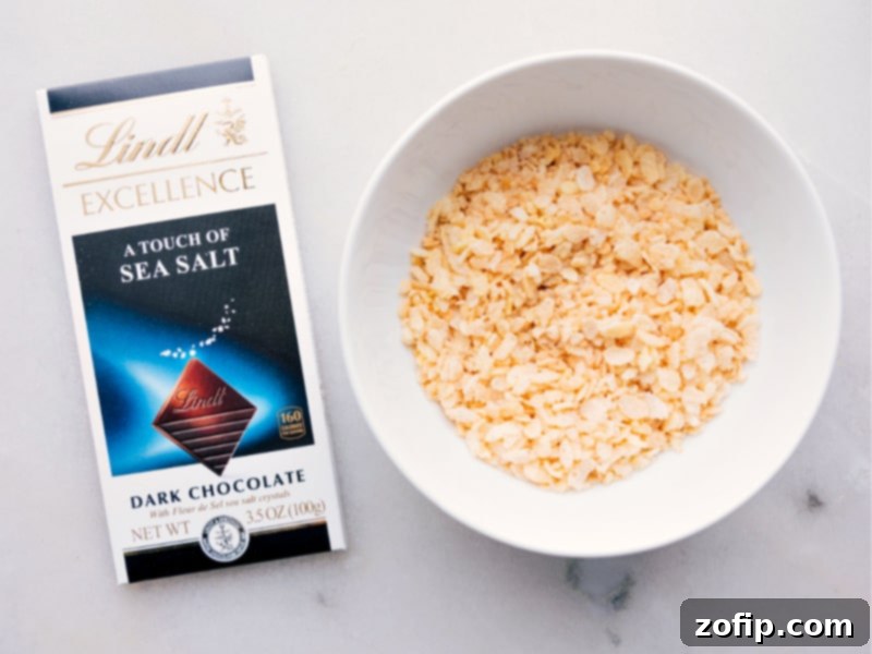 Close-up image of a hand picking up a piece of homemade Buncha Crunch, highlighting the glossy chocolate and visible crispy rice cereal.