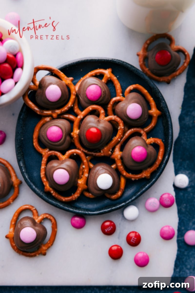Valentine's Day is just around the corner, and what better way to show your love than with some homemade treats? These simple Valentine's Pretzels are not only delicious but also make a great edible gift. Recipe via ChelseasMessyApron.com #valentines #chocolate #pretzels #doves #m&ms #easy #treats A festive plate of Valentine's Pretzels adorned with red and pink M&Ms.