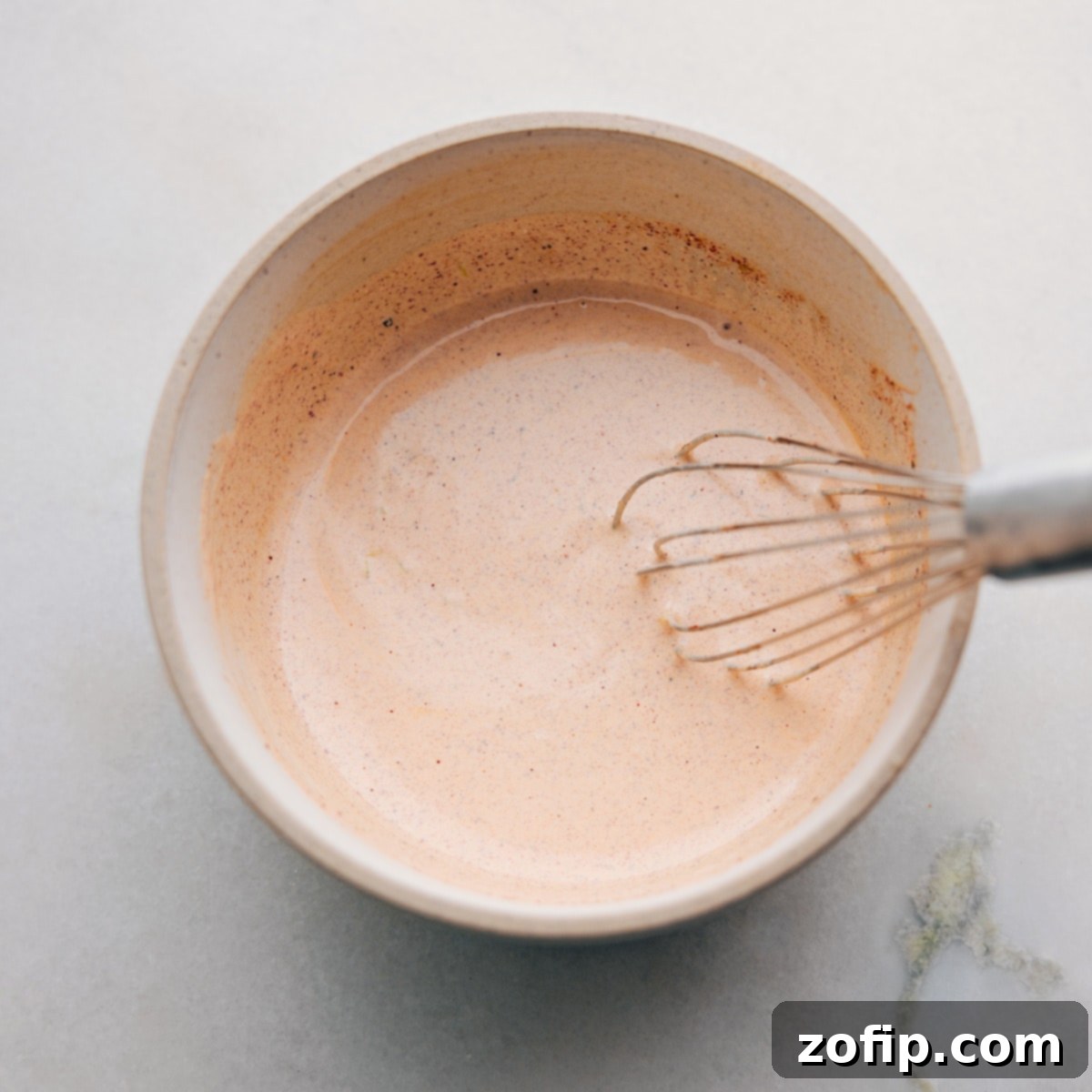 Ingredients for the creamy dressing, including mayo, sour cream, lime juice, chili powder, paprika, and cumin, arranged in small bowls, ready to be whisked.