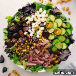 Delicious Arugula Salad with figs, salami, cucumber, pistachios, and goat cheese, served in a white bowl.