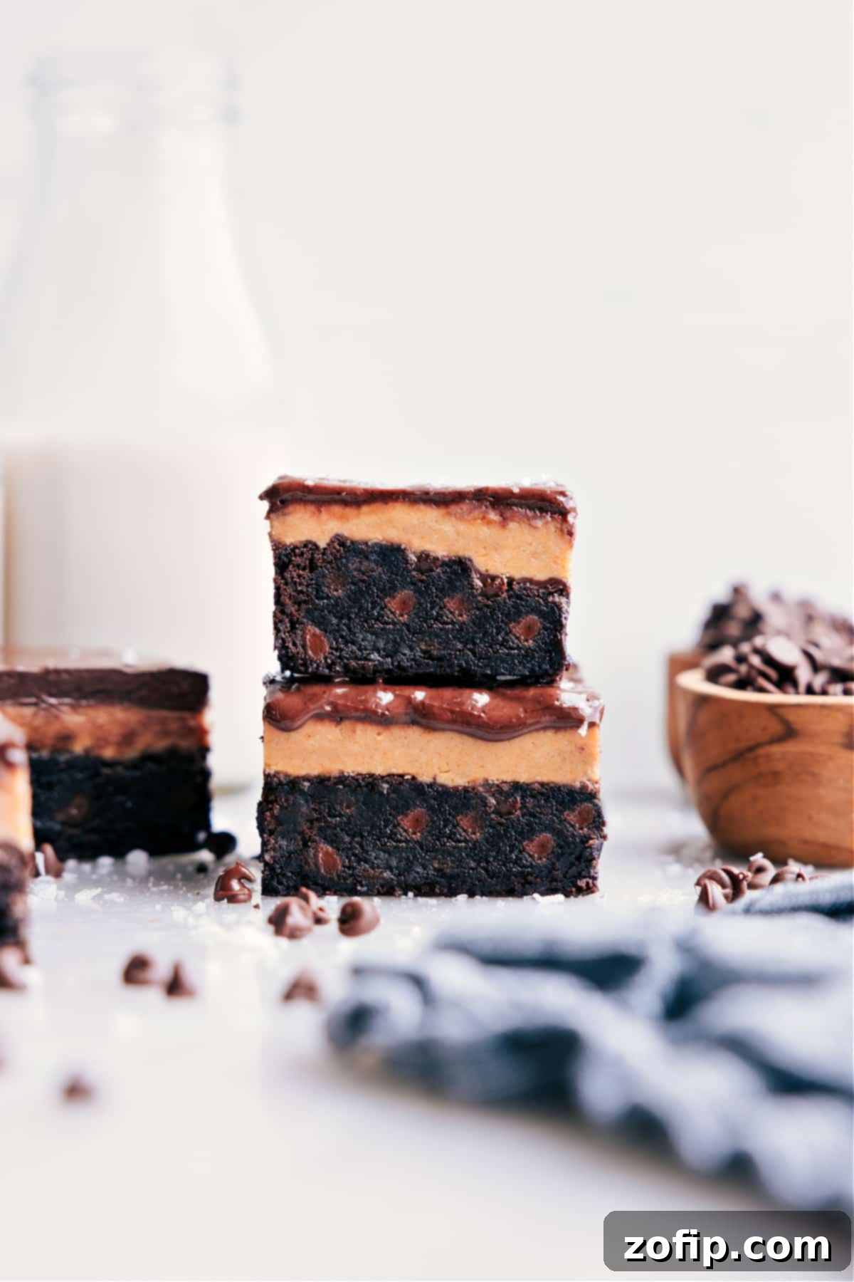 Stacked Buckeye Brownies show off their yummy layers of fudgy chocolate, creamy peanut butter, and smooth chocolate ganache, ready to be enjoyed.