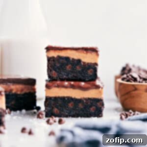 A delicious slice of Buckeye Brownies with distinct layers of chocolate brownie, creamy peanut butter, and shiny chocolate topping.