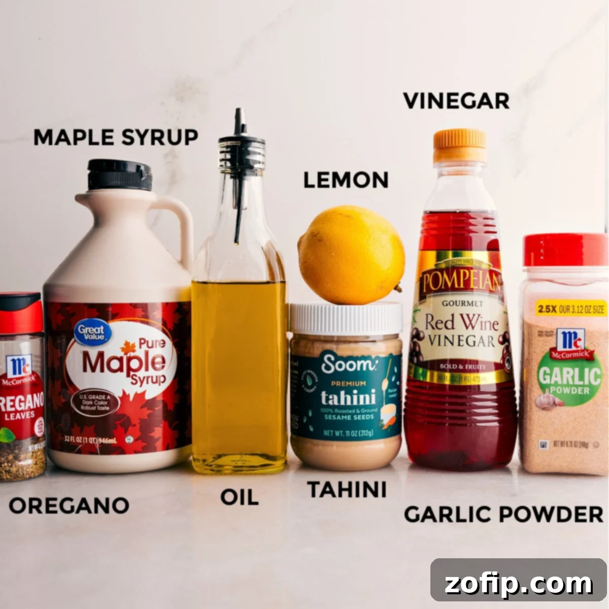 The dressing ingredients for the grain bowl—maple syrup, seasonings, lemon, tahini, and vinegar—are prepped for easy assembly, highlighting the delicious flavor profile.