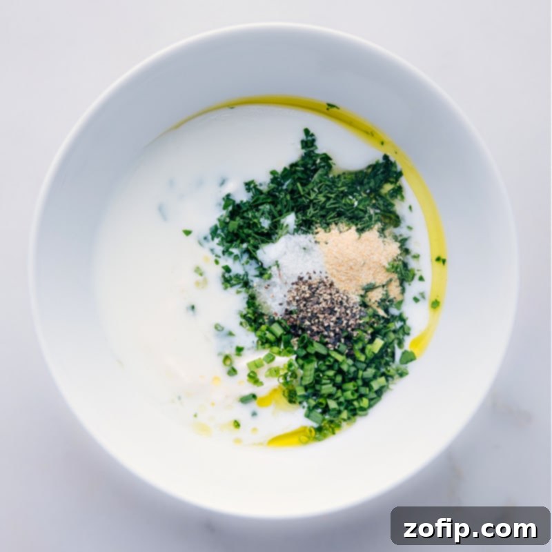 Adding buttermilk to achieve the perfect creamy consistency and tangy flavor for your Ranch Dressing. Process shot of buttermilk being poured into a bowl with other Ranch Dressing ingredients, highlighting the creamy texture