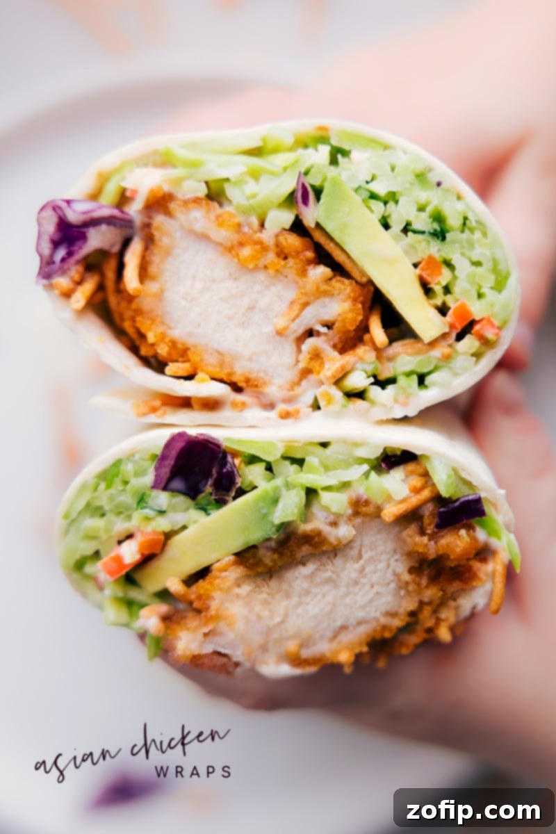 The Ultimate Asian Chicken Wraps Recipe Display Asian Chicken Wraps cut in half, revealing the layers of crispy chicken, colorful slaw, and chow mein noodles inside.