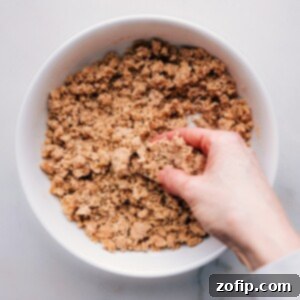 The Ultimate Streusel Guide 5 A hand mixes streusel ingredients in a bowl, showing the formation of coarse, buttery crumbs perfect for topping baked goods.