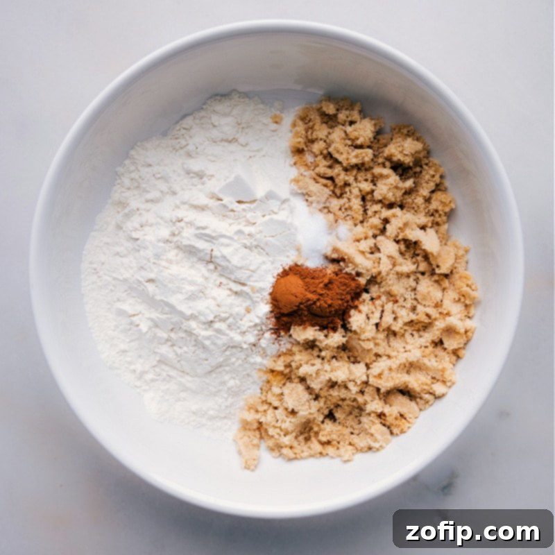 Unlock the secret to perfect streusel with our easy recipe, using simple ingredients like flour, brown sugar, and spices to create a crunchy, sweet topping. Learn how to make streusel perfectly every time! Recipe via chelseasmessyapron. A bowl containing flour, brown sugar, and aromatic spices, carefully measured and ready for mixing into the streusel recipe.