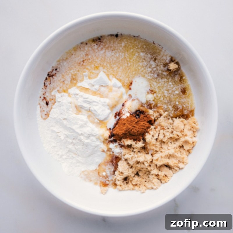 Follow our handy guide to effortlessly make the perfect streusel for your next dessert. This quick and easy recipe, via chelseasmessyapron, ensures a delicious topping every time! Melted butter being poured into a bowl of dry ingredients for streusel, illustrating a key step in creating the crumbly topping.