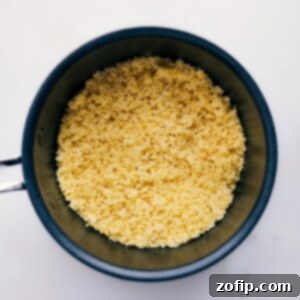 Close-up of fluffy cooked couscous in a white bowl.