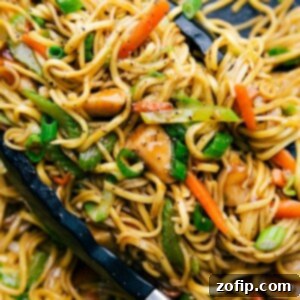 Chicken chow mein in a skillet with tongs, filled with fresh vegetables, perfectly cooked and seasoned.