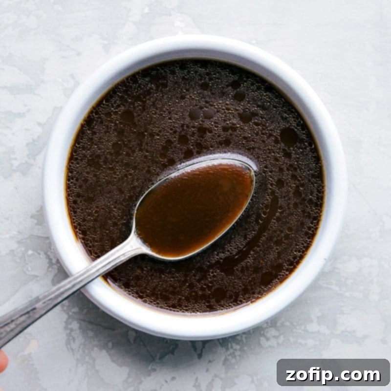 Rich, savory chow mein sauce being drizzled over the stir-fried chicken and vegetables, ready to be tossed with noodles.
