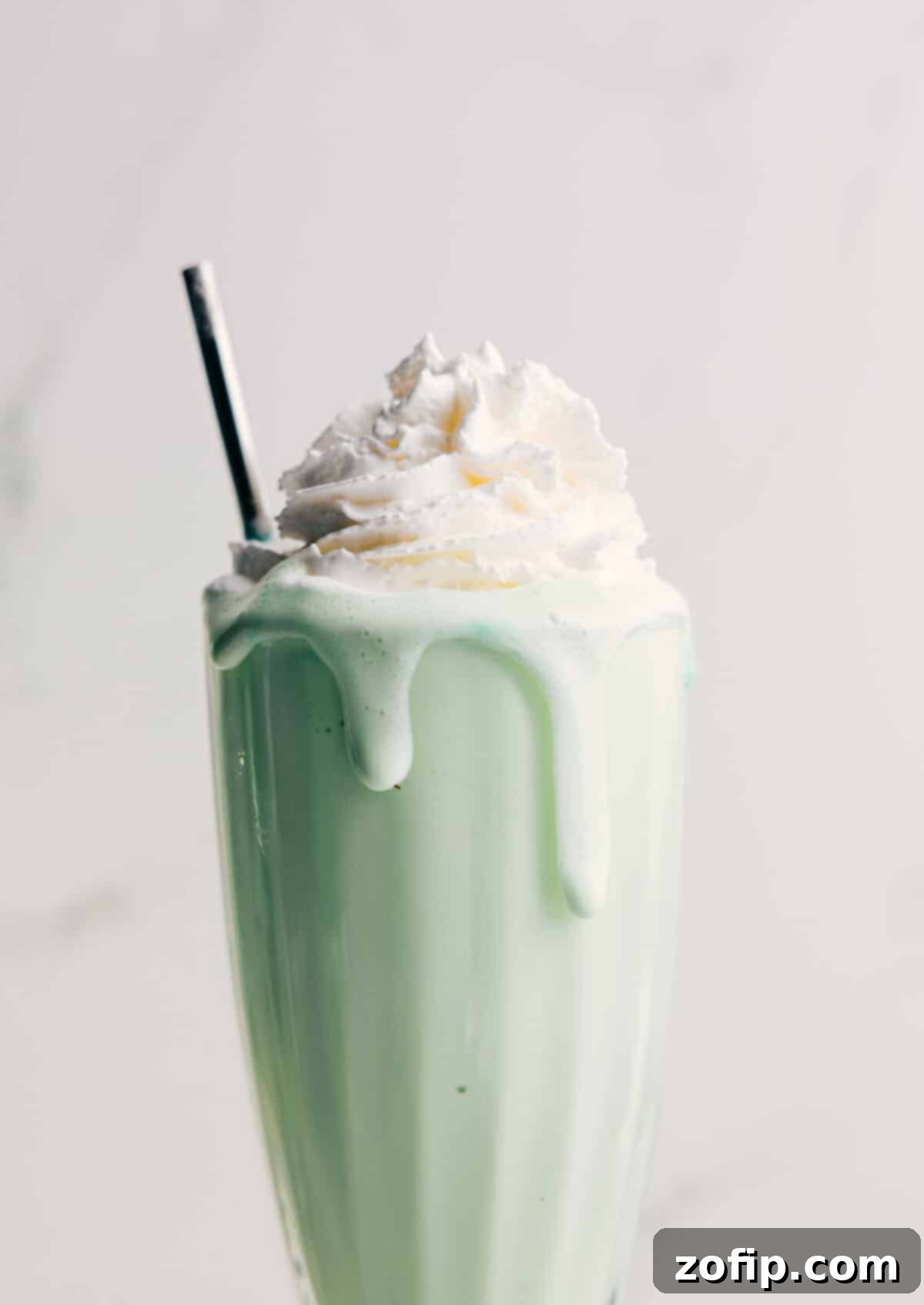 Thick, creamy homemade Shamrock Shake topped with fresh whipped cream and a cherry.
