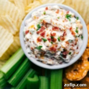 Ultimate Baked Potato Dip 4 Baked potato dip creamy and topped with herbs and bacon surrounded by potato chips and celery sticks.