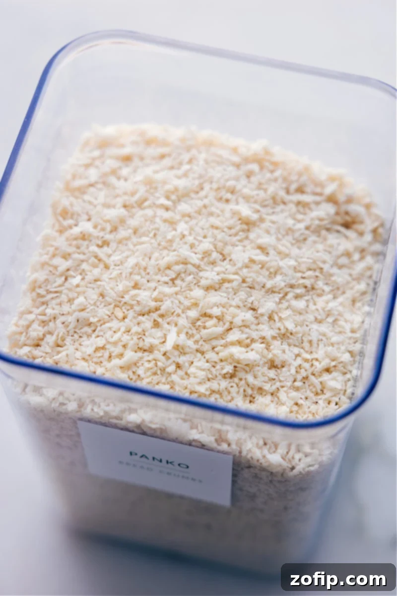 Overhead view of an open container of panko breadcrumbs on a wooden surface.