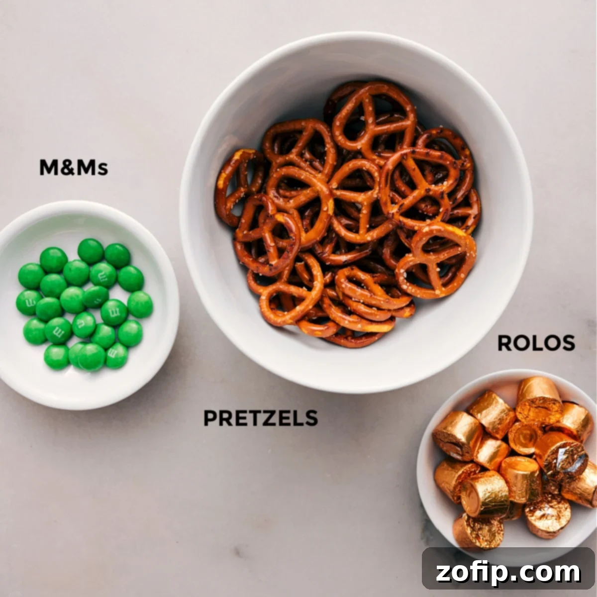 The three essential ingredients for Leprechaun Thumbprints: crunchy pretzels, gooey Rolos, and vibrant green M&M's, ready for assembly.