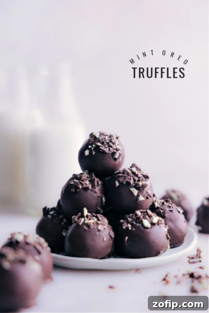 Stack of perfectly coated Mint Oreo Truffles, garnished with chopped Andes mints, on a rustic background.