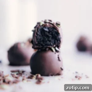 A close-up of a finished Mint Oreo Truffle, showcasing its smooth chocolate coating and a sprinkle of green and white for garnish.