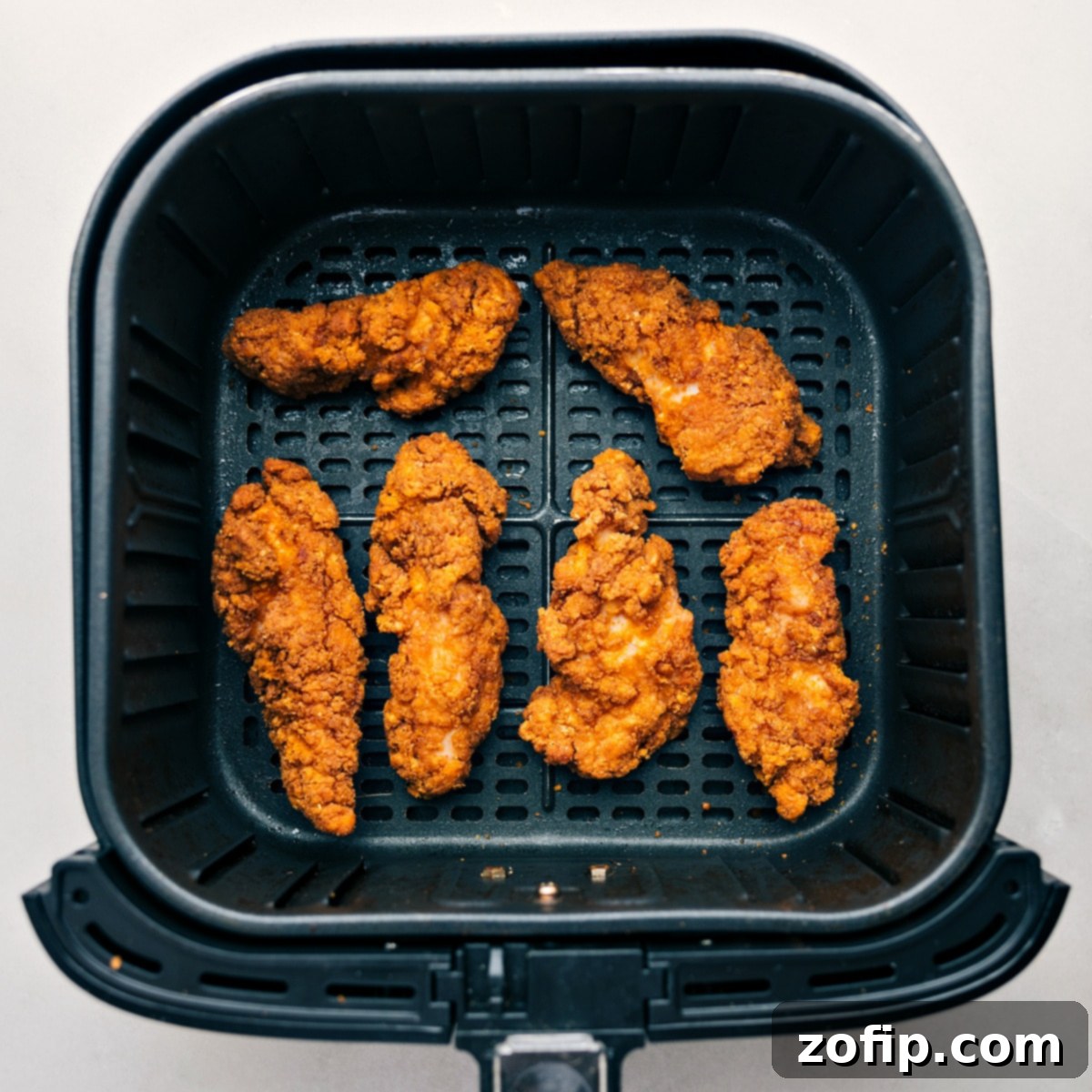 Crispy chicken strips, freshly cooked in an air fryer, ready to be coated in buffalo sauce and added to the wraps.