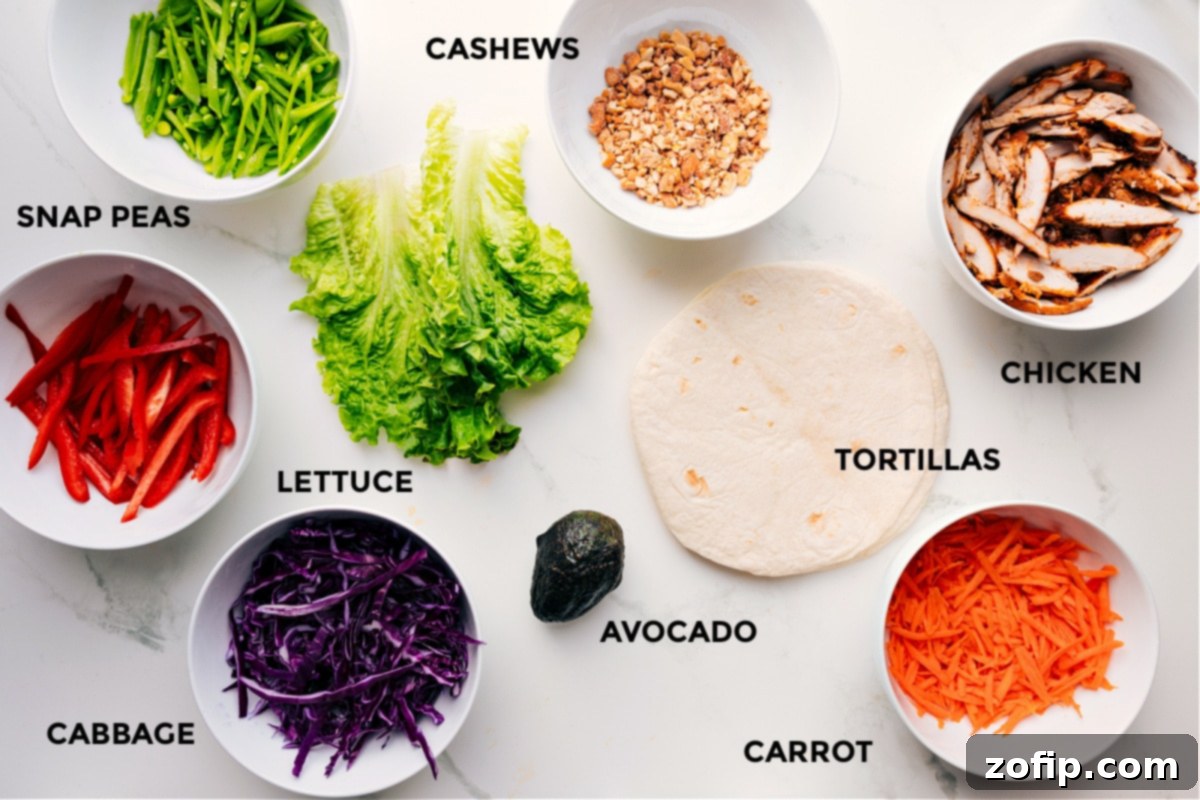 A vibrant display of fresh ingredients for Cashew Chicken Wraps, including snap peas, bell peppers, cashews, cooked chicken, tortillas, avocado, lettuce, and shredded cabbage, all prepped for easy assembly.