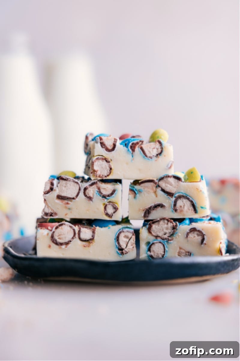 Image of Robin Egg Fudge squares stacked elegantly on a plate, showcasing the creamy white base and colorful candy bits for a delightful dessert.