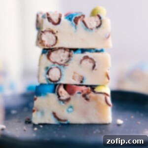 A top-down view of a serving of Robin Egg Fudge, showcasing its smooth white chocolate base and vibrant, colorful candy pieces.