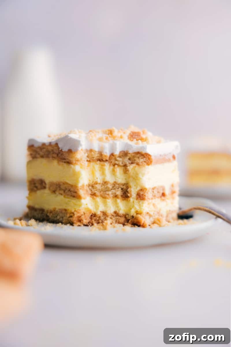 A close-up image of a single slice of Lemon Icebox Cake with a bite taken out, showcasing the moist layers of cookie and creamy lemon filling.