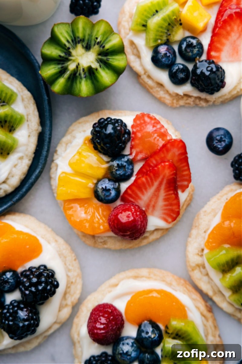 Overhead shot of an entire platter of beautiful Sugar Cookie Fruit Pizzas, garnished with a variety of fresh berries and mandarin oranges, ready for serving.