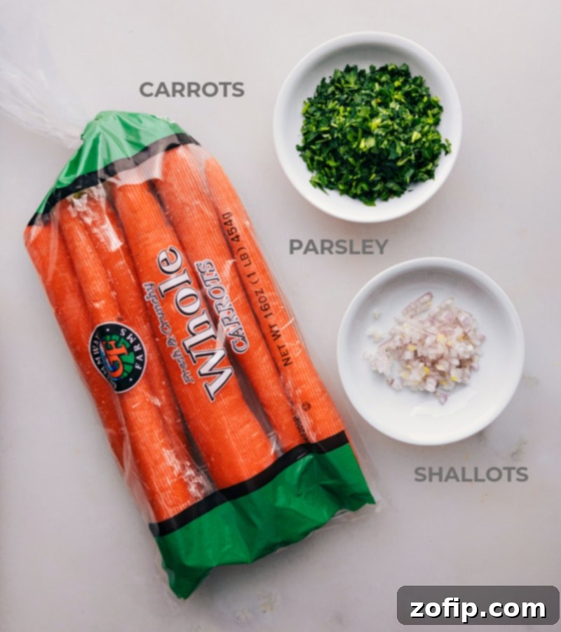 A collection of fresh ingredients for French Carrot Salad including whole carrots, shallots, parsley, lemon, olive oil, Dijon mustard, and honey.