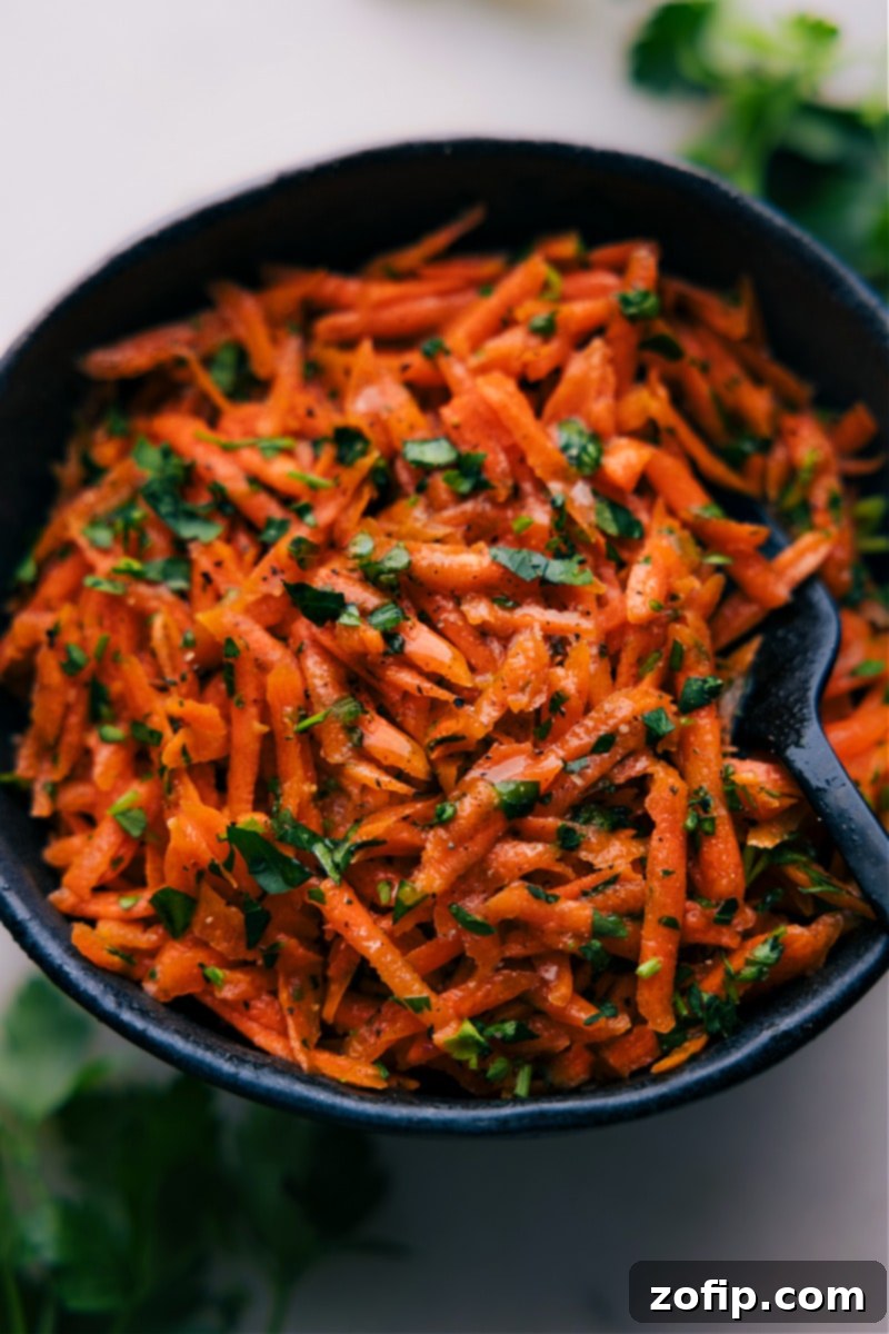 Up-close overhead image of the French Carrot Salad served in a white bowl, ready to be enjoyed with a fork.